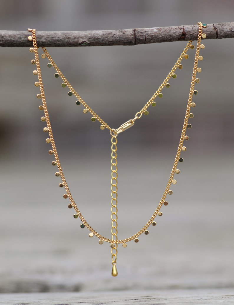 Puede incluir: Un collar de cadena de oro con un delicado colgante y peque&ntilde;os abalorios redondos que cuelgan de la cadena.