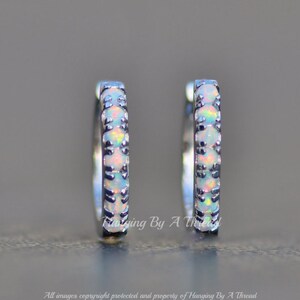 May include: A pair of silver hoop earrings with a row of white opal stones set in the band.