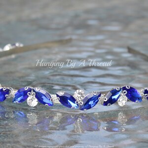 Pu&ograve; includere: Un cerchietto argentato con una fila di strass blu e trasparenti. Il cerchietto &egrave; decorato con strass a forma di marquise.