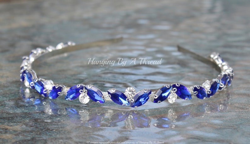 Pu&ograve; includere: Un cerchietto argentato con una fila di strass blu e trasparenti. Il cerchietto &egrave; decorato con strass a forma di marquise.