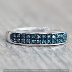 May include: A silver band ring with two rows of small, blue diamonds.