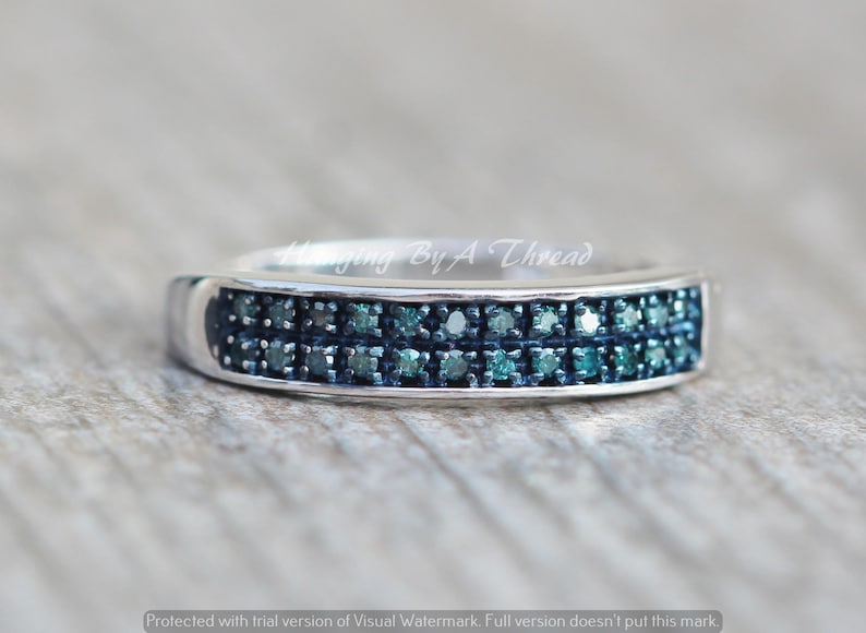 May include: A silver band ring with two rows of small, blue diamonds.