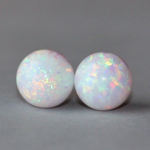 May include: A pair of white opal stud earrings with iridescent rainbow flecks.