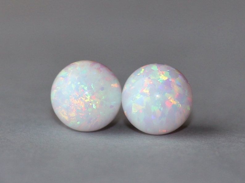 May include: A pair of white opal stud earrings with iridescent rainbow flecks.