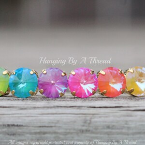 May include: A rainbow-colored crystal bracelet with gold accents. The bracelet features round, faceted crystals in shades of yellow, green, blue, pink, and orange.