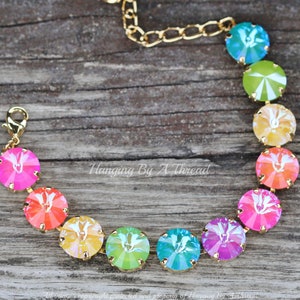May include: A rainbow crystal bracelet with gold chain and clasp. The bracelet features round, faceted crystals in shades of pink, orange, yellow, green, blue, and purple.