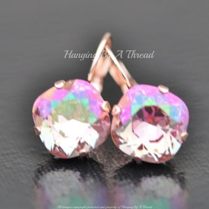 May include: Rose gold earrings with iridescent pink square-shaped crystals. The earrings have a lever back closure.