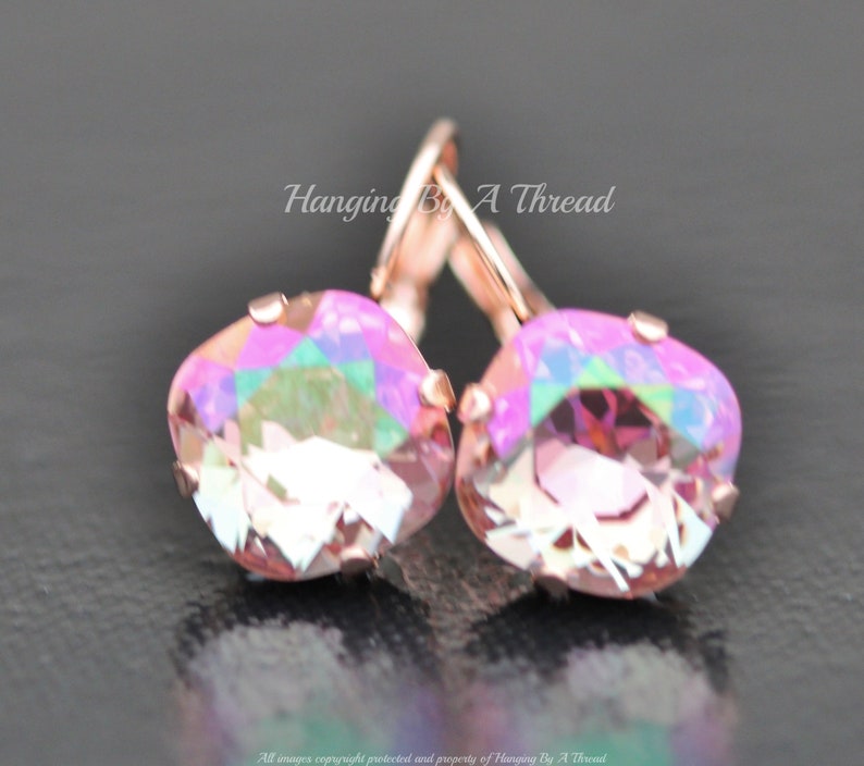 May include: Rose gold earrings with iridescent pink square-shaped crystals. The earrings have a lever back closure.