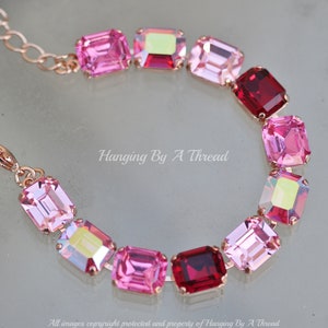 May include: A rose gold bracelet with a chain and alternating pink and red square-shaped crystals.