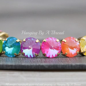 May include: A rainbow-colored crystal bracelet with gold settings. The bracelet features a row of round, faceted crystals in shades of yellow, green, blue, purple, pink, and orange.