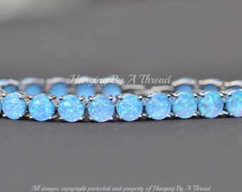 May include: A silver bracelet with a row of light blue opal stones.