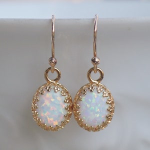 May include: Gold earrings with a white opal stone set in a delicate filigree design.