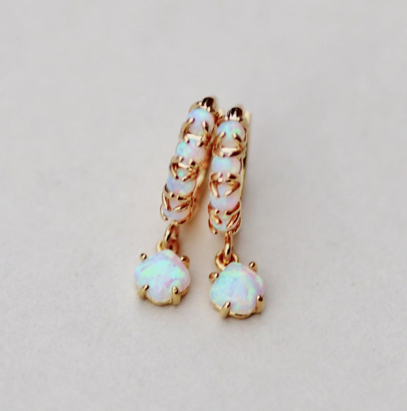 Puede incluir: Aretes de aro de oro con una piedra de &oacute;palo colgante. Los aros est&aacute;n hechos de un alambre delicado y est&aacute;n adornados con peque&ntilde;as piedras de &oacute;palo.