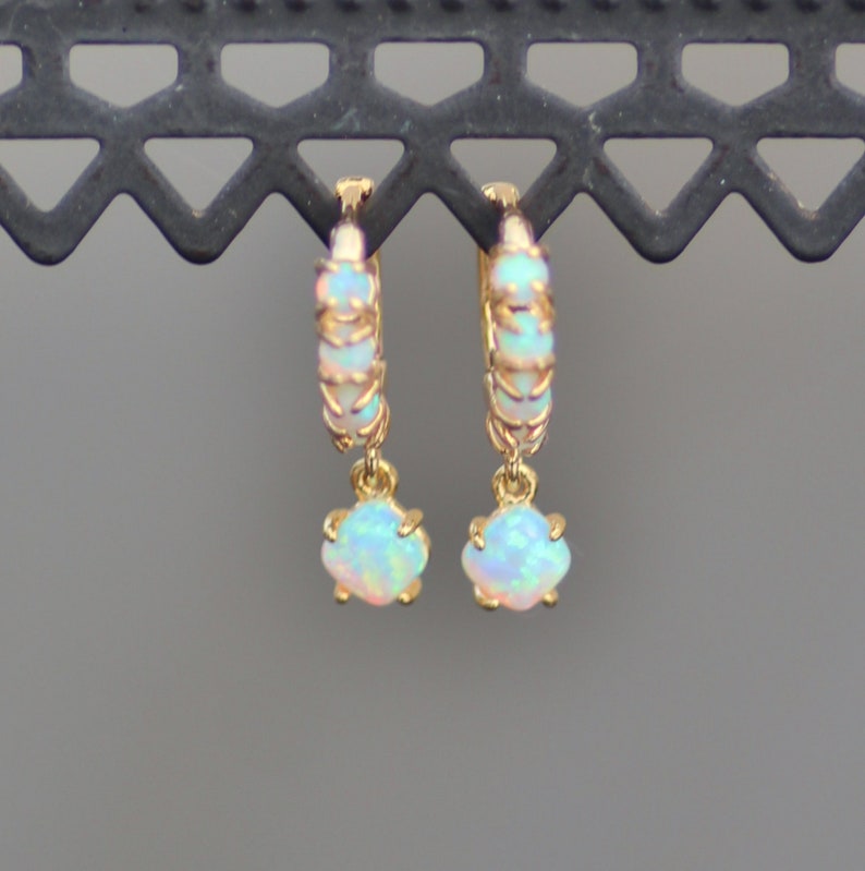 Puede incluir: Aretes de aro de oro con una piedra preciosa de &oacute;palo colgante. Los aros est&aacute;n engastados con peque&ntilde;os &oacute;palos.