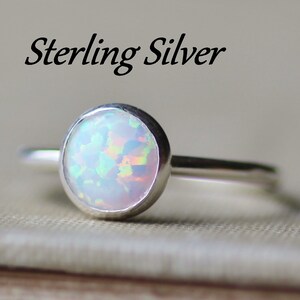 May include: A sterling silver ring with a white opal gemstone. The ring is simple and elegant, with a smooth band and a round opal.