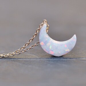Op de afbeelding: Een delicate gouden ketting met een halve maan hanger gemaakt van iriserende witte opaal.