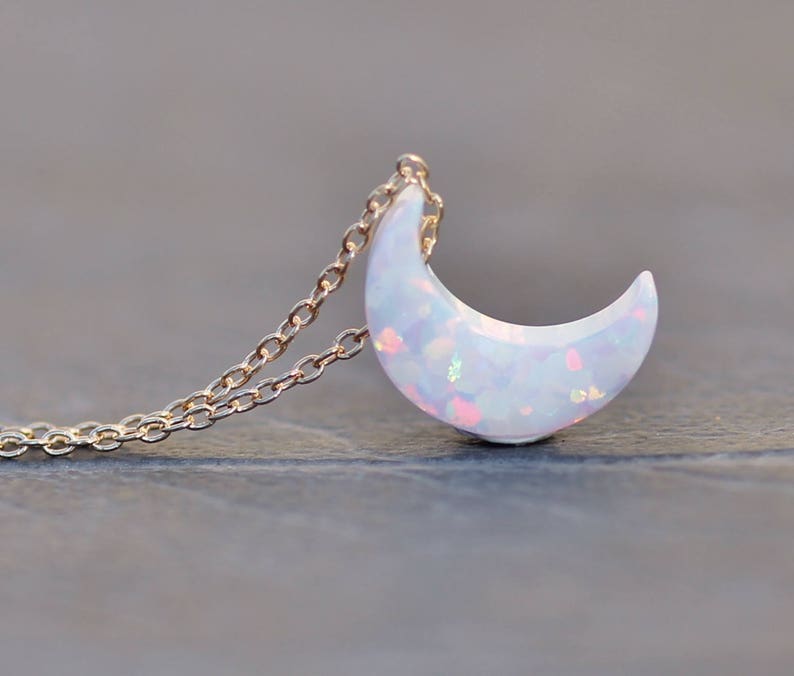 Op de afbeelding: Een delicate gouden ketting met een halve maan hanger gemaakt van iriserende witte opaal.