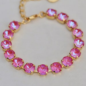 May include: A gold chain bracelet with pink iridescent round stones.