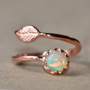 May include: A rose gold ring with a delicate leaf design and a round opal gemstone.