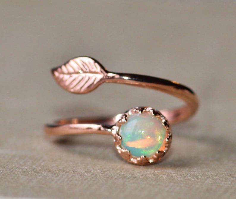 May include: A rose gold ring with a delicate leaf design and a round opal gemstone.