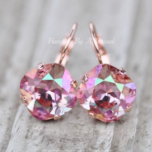 May include: Rose gold earrings with pink iridescent crystal stones. The earrings have a lever back closure.