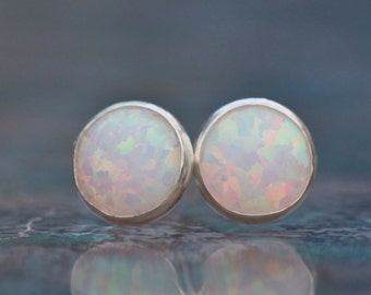 May include: A pair of silver stud earrings with white opal stones.