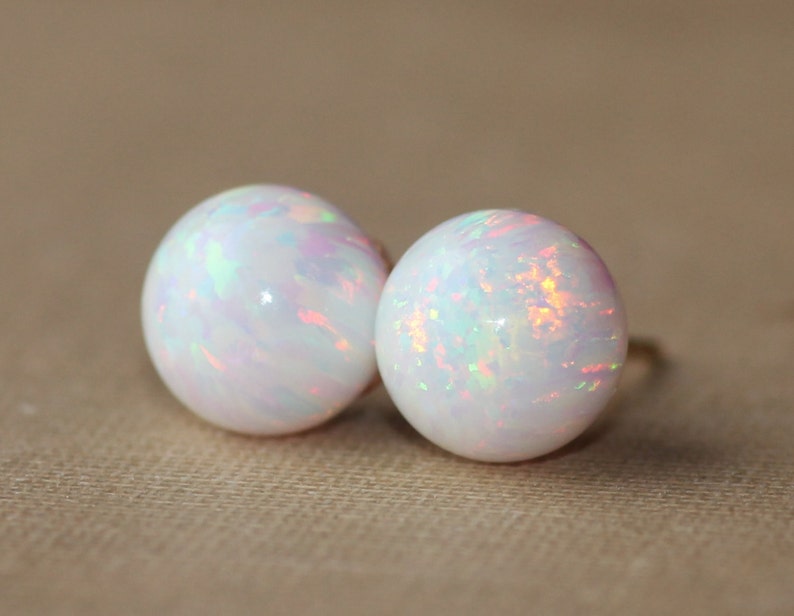 May include: A pair of white opal stud earrings with iridescent rainbow colors.
