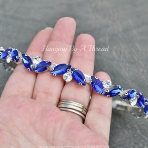 Pu&ograve; includere: Un cerchietto argentato con strass blu e trasparenti disposti a forma di foglie. Il cerchietto &egrave; flessibile e pu&ograve; essere regolato per adattarsi alla maggior parte delle dimensioni della testa.