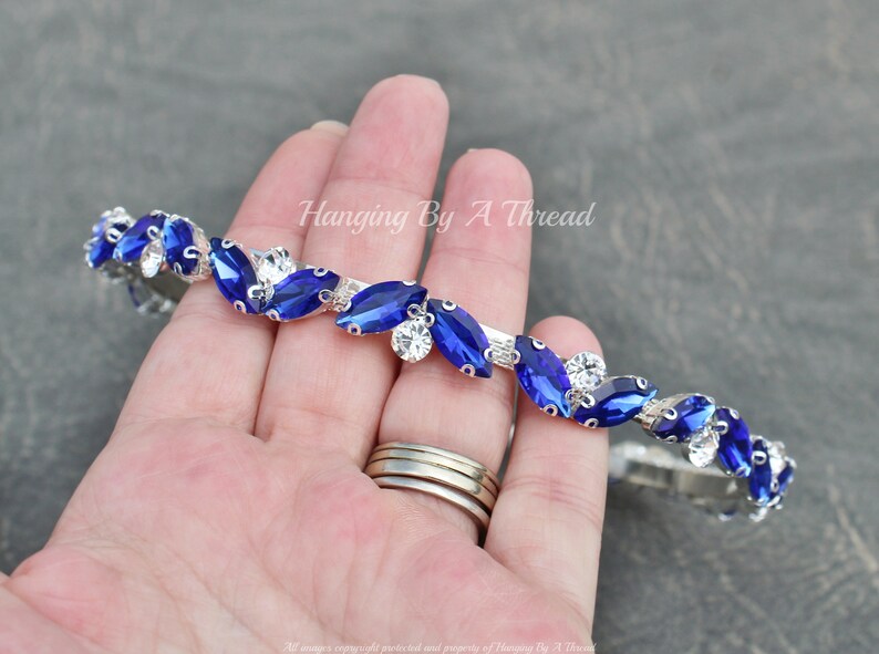 Pu&ograve; includere: Un cerchietto argentato con strass blu e trasparenti disposti a forma di foglie. Il cerchietto &egrave; flessibile e pu&ograve; essere regolato per adattarsi alla maggior parte delle dimensioni della testa.