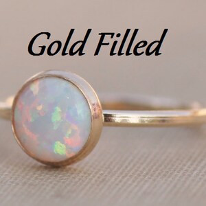 May include: A gold filled ring with a white opal gemstone. The ring is simple and elegant, perfect for everyday wear.