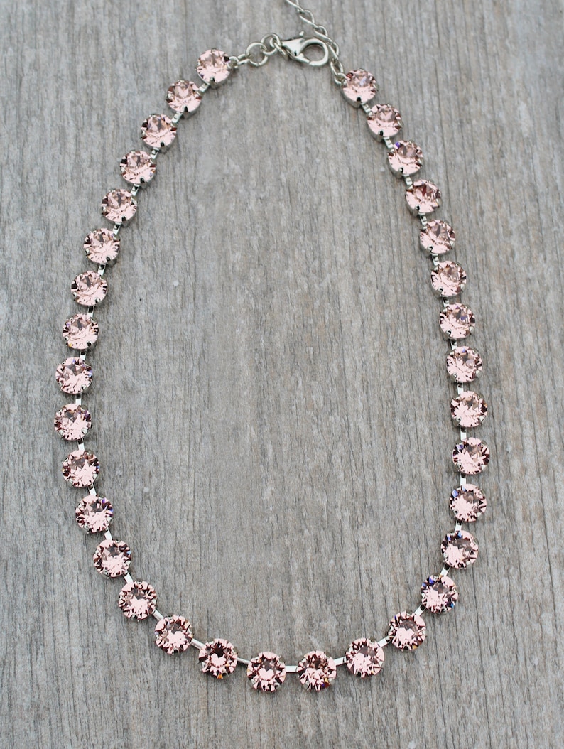 May include: A delicate silver chain necklace with a row of pale pink crystal stones.