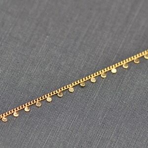 Puede incluir: Un collar de cadena dorada con peque&ntilde;os colgantes redondos.