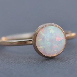 May include: A delicate gold ring with a white opal gemstone. The opal has a subtle iridescent shimmer.