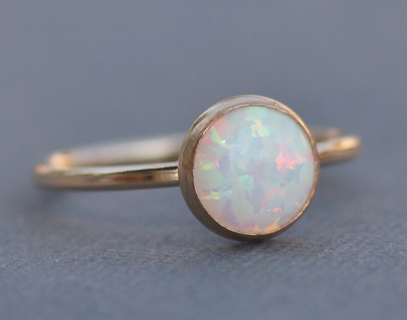 May include: A delicate gold ring with a white opal gemstone. The opal has a subtle iridescent shimmer.