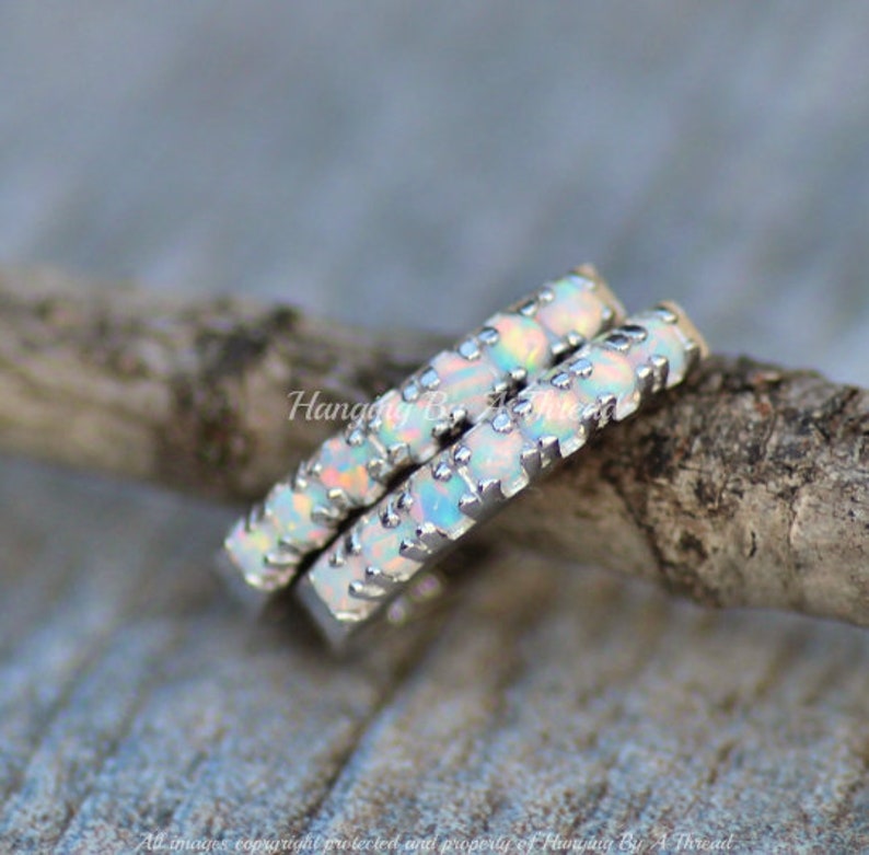 May include: Two silver rings with white opal stones set in a pave setting. The rings are stacked on top of each other.
