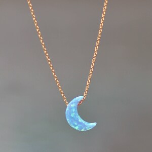 Op de afbeelding: Een delicate gouden ketting met een halve maan hanger gemaakt van blauwe opaal.