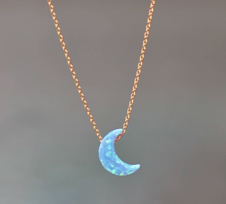 Op de afbeelding: Een delicate gouden ketting met een halve maan hanger gemaakt van blauwe opaal.