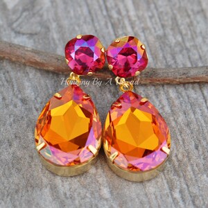 May include: Gold dangle earrings featuring a teardrop-shaped orange and pink iridescent crystal, with a smaller square pink iridescent crystal.