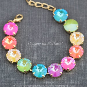 May include: A gold chain bracelet with a rainbow of iridescent crystal beads. The beads are arranged in a gradient from pink to green. The bracelet has a lobster claw clasp.