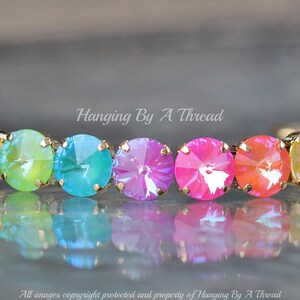 May include: A rainbow-colored crystal bracelet with gold-toned metal accents. The bracelet features a row of round, faceted crystals in shades of red, orange, yellow, green, blue, and purple.