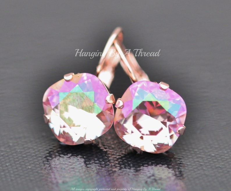 May include: Rose gold earrings with iridescent pink square crystals. The earrings have a lever back closure.