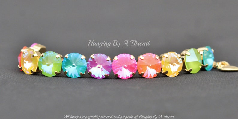 May include: Rainbow crystal bracelet with gold accents. The bracelet features a row of round, iridescent crystals in a rainbow color sequence.