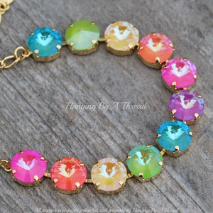 May include: A rainbow-colored crystal necklace with gold accents. The necklace is made of round, faceted crystals in shades of blue, green, yellow, orange, pink, and purple. The crystals are strung on a gold chain.