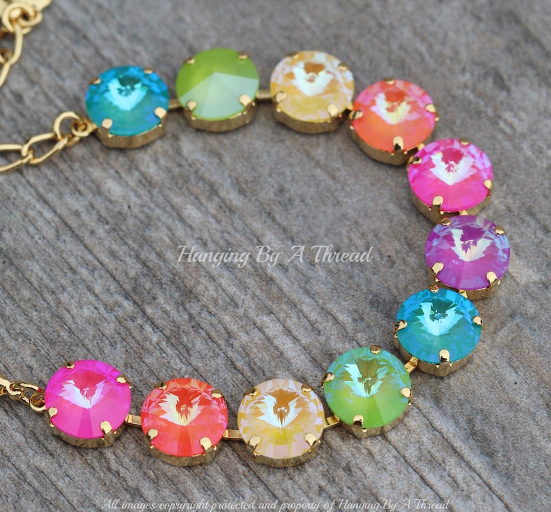 May include: A rainbow-colored crystal necklace with gold accents. The necklace is made of round, faceted crystals in shades of blue, green, yellow, orange, pink, and purple. The crystals are strung on a gold chain.
