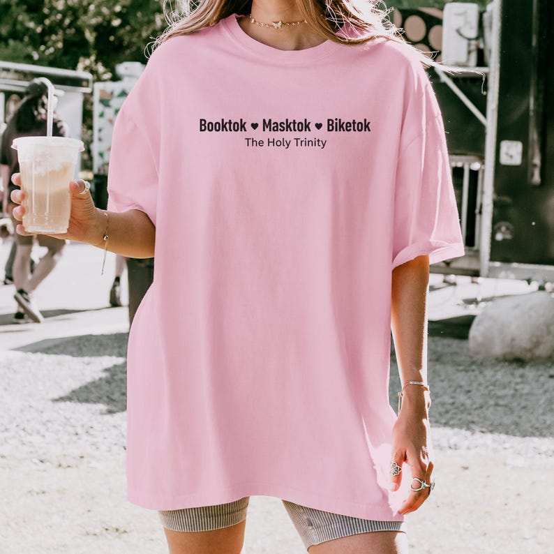 Pu&ograve; includere: T-shirt rosa chiaro oversize con la scritta nera "Booktok Masktok Biketok The Holy Trinity". La maglietta &egrave; realizzata in materiale morbido e ha maniche corte.