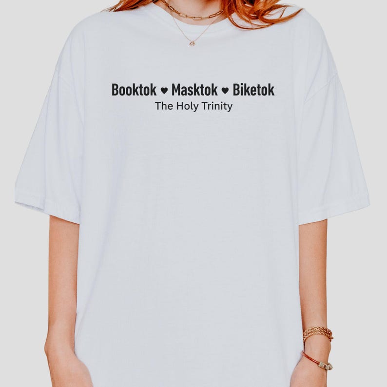 Pu&ograve; includere: T-shirt bianco con testo nero che recita "Booktok Masktok Biketok" sopra "The Holy Trinity". La maglietta ha maniche corte e una vestibilit&agrave; rilassata. Il testo &egrave; centrato sul petto.