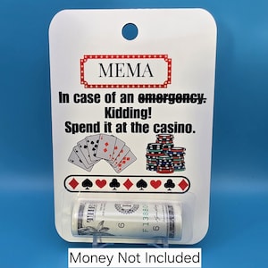 May include: A white rectangular card with a hole at the top, featuring the text MEMA, In case of an emergency. Kidding! Spend it at the casino. It displays playing cards, poker chips, and card suits. A clear plastic tube holds a rolled bill.