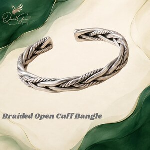 May include: A silver-toned braided open cuff bangle featuring a textured, rope-like design with an oxidized finish. The metal band is shaped into an open circle, displaying intricate twisted strands that form a continuous braided pattern throughout.
