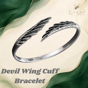 May include: An open cuff bracelet crafted from silver-toned metal, featuring two detailed wing designs that meet at the center. The band is engraved with the text S925 on the inner surface, indicating the metal composition.