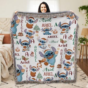 A woman is holding up a blanket with a repeating pattern of Ariel characters from the Disney movie Lilo and Stitch.